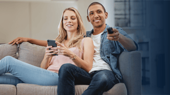 couple watching tv and looking at a gift card on their phone