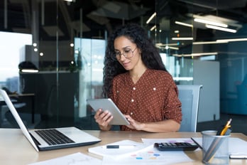 hr manager sitting at desk using several tech tools