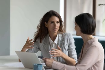 two program managers discussing their gift card company in front of a laptop